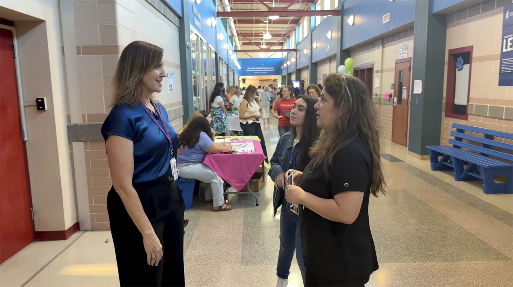 Woman speaking with two people at a school setting