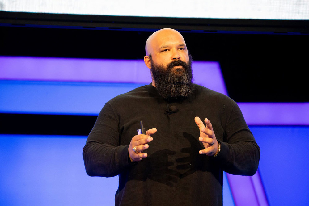 Stephen Mackey standing with two students in front of classroom during presentation on leadership