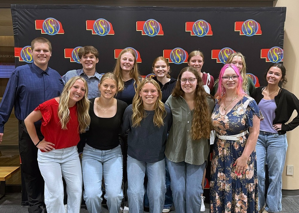 Gretna High School Journalism team from Gretna Media posing in front of the NSAA banner at state awards