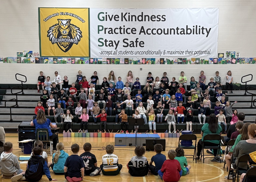 2nd grade students performing while standing on the bleachers in the gym.