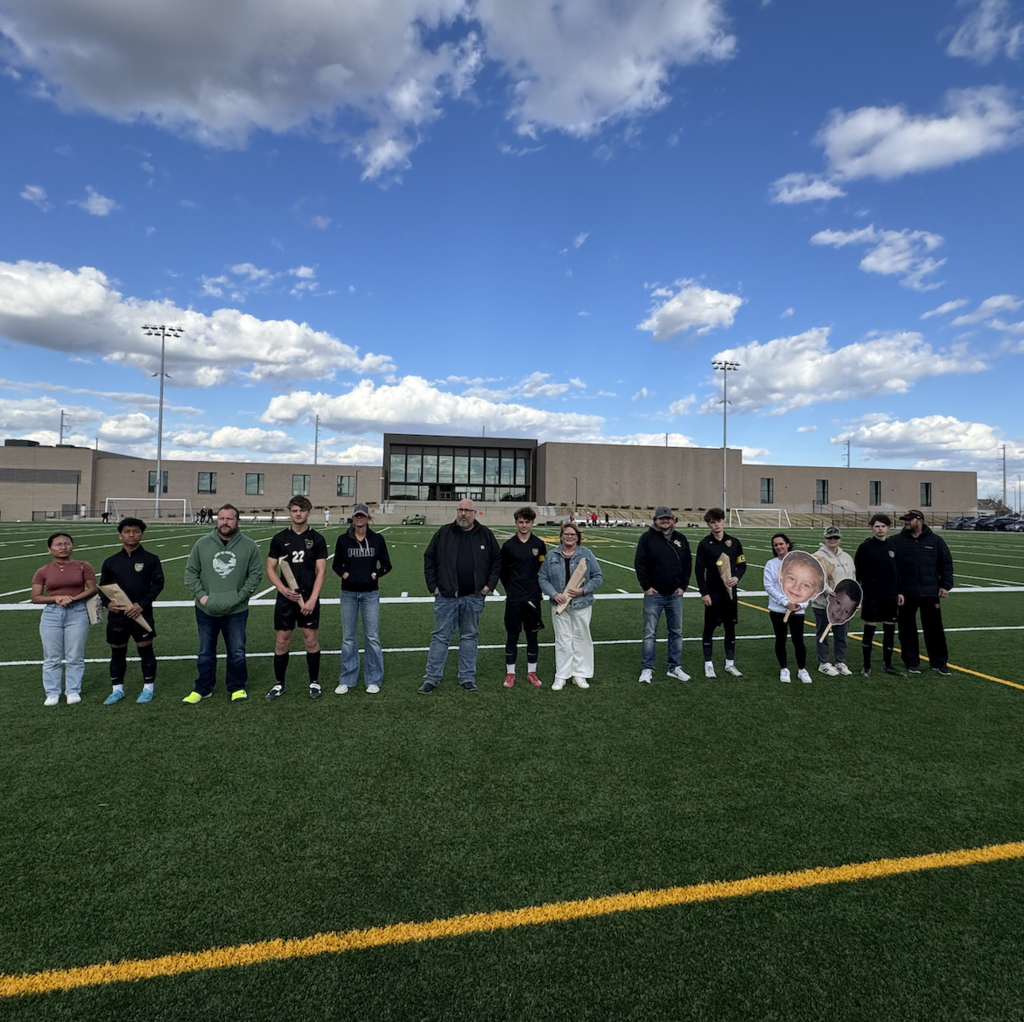 A group of Gretna East Soccer players and their parents holding flowers being honored for Senior Night.