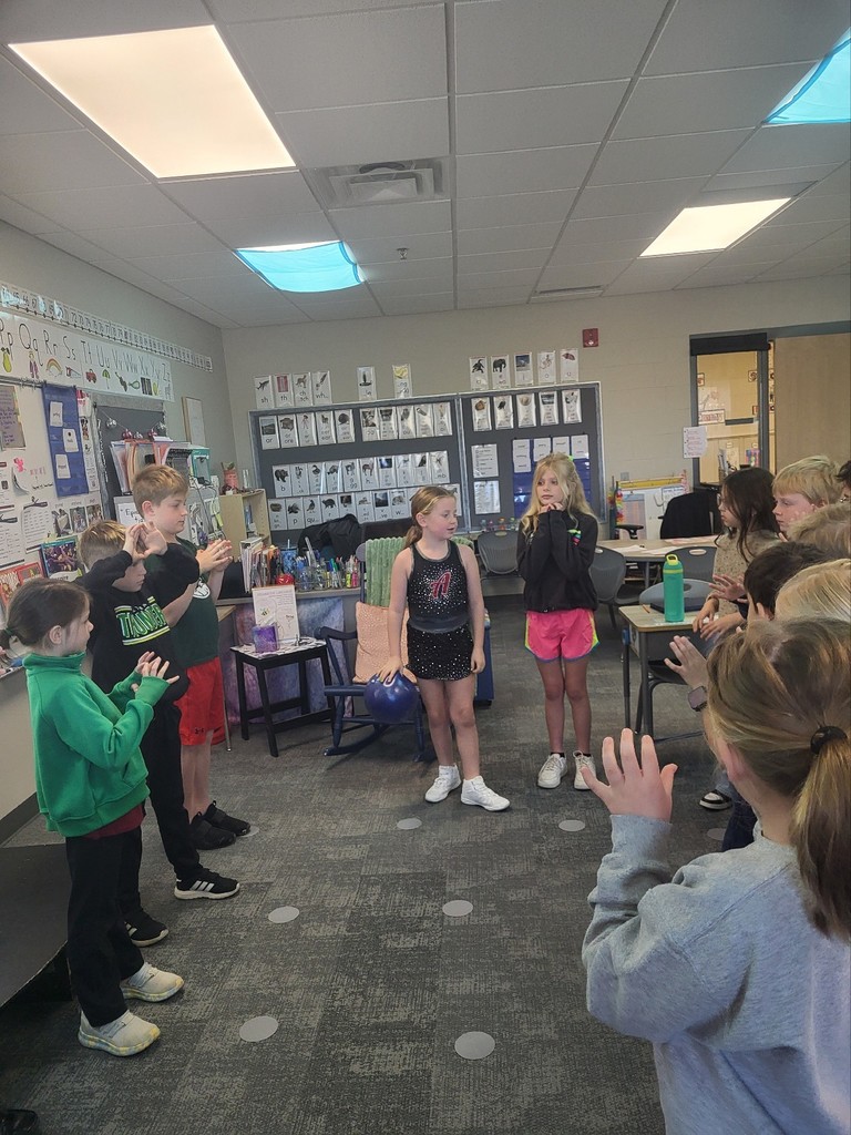 students stand in a circle passing a ball