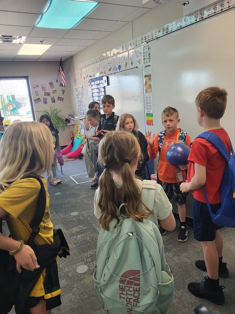 students stand in a circle passing a ball