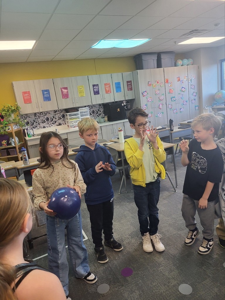 students stand in a circle passing a ball