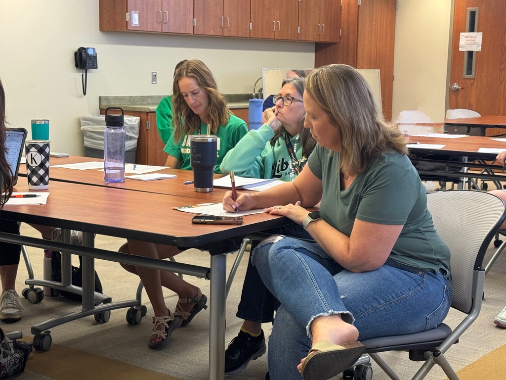 Three GPS staff members nurse and secretaries sitting at a desk in conference room takings notes