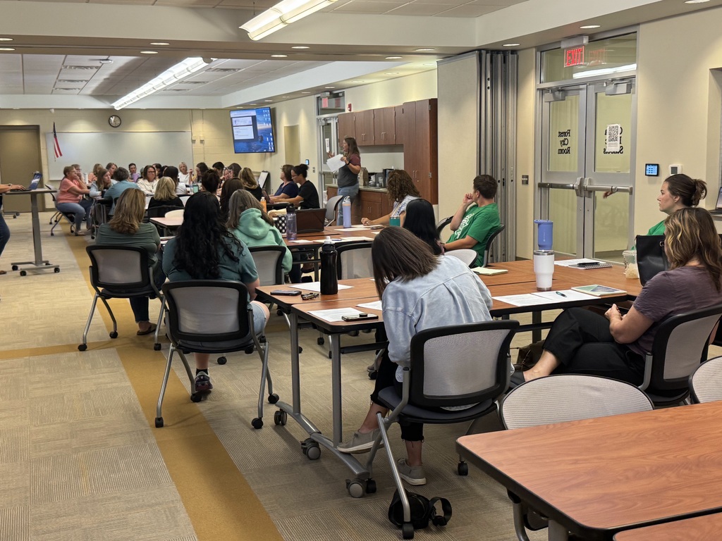 conference room filled with secretaries and nurses with slideshow projecting on television screens