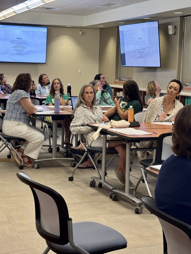 Ten secretaries and nurses at several different tables in conference room with television projecting slideshow