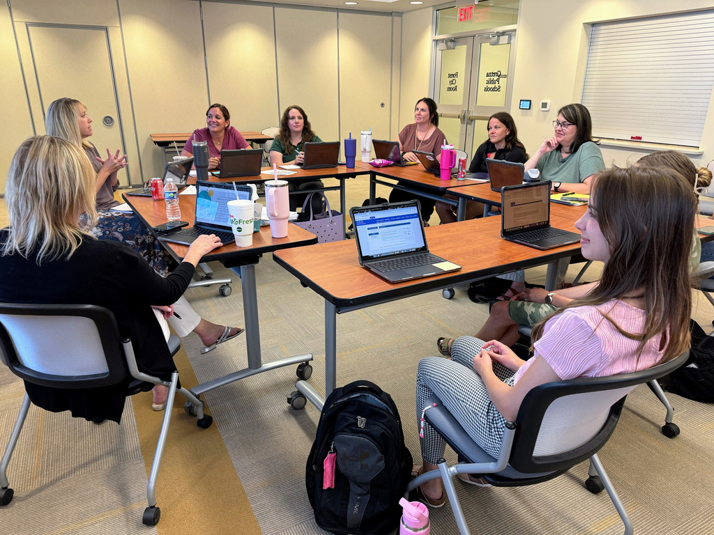 Group of GPS staff members engaged in a discussion in large conference room