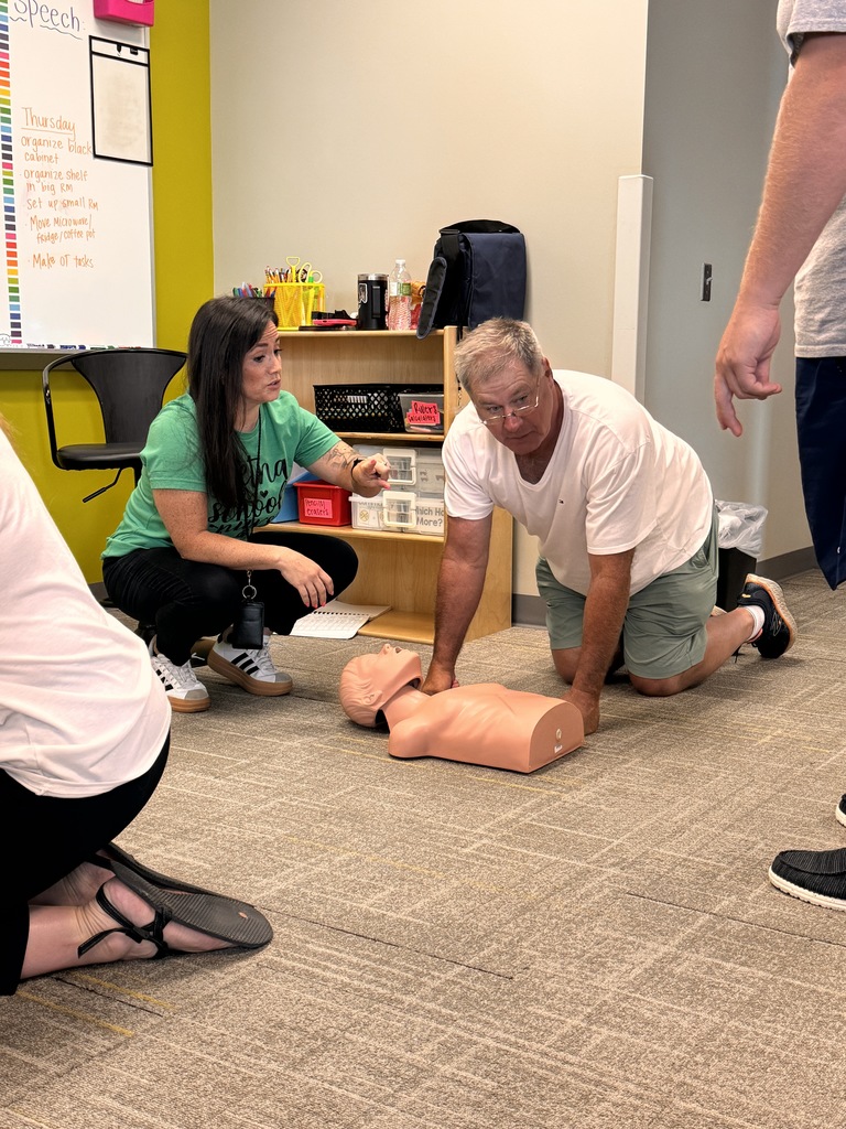 nurse directing staff member of gretna public schools on cpr training on a mannequin