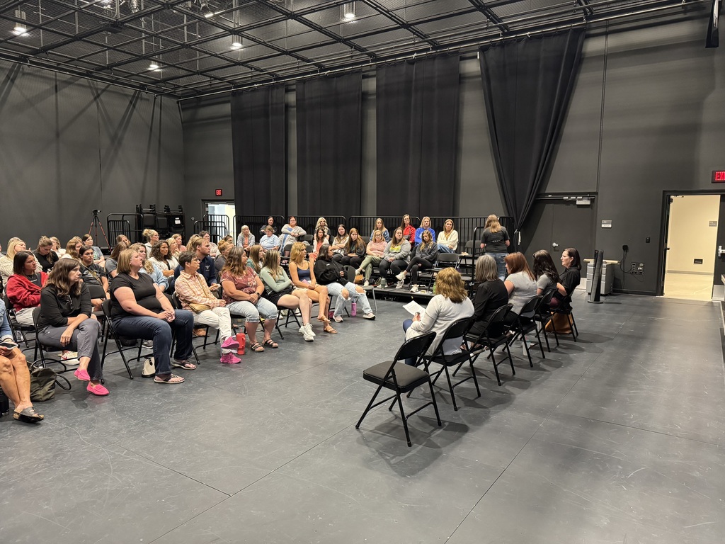 a large group of paraprofessionals sitting in the "black box" at Gretna East High School listening to five presenters about Special Education training