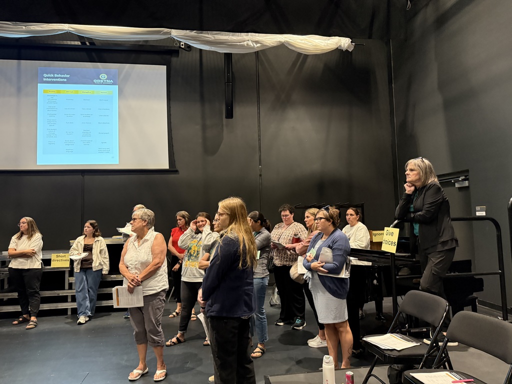 a group of paraprofessionals standing in the "black box" at Gretna East High School for special education training