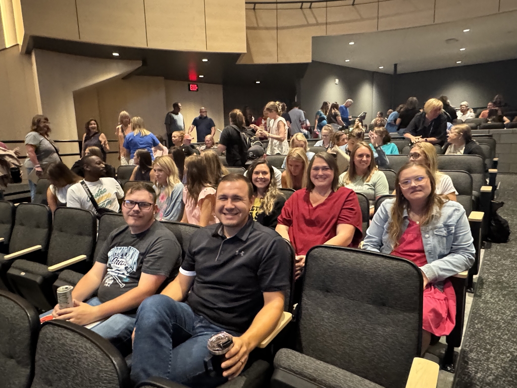 a group of staff members sitting in auditorium seating at GEHS smiling for camera
