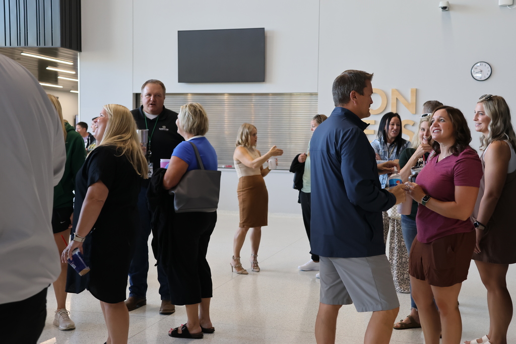 board member with staff members talking in groups in cafeteria