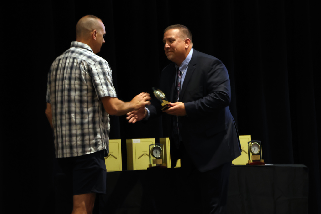 Superintendent Travis Lightle shaking hands with a staff member earning 20 years of service award