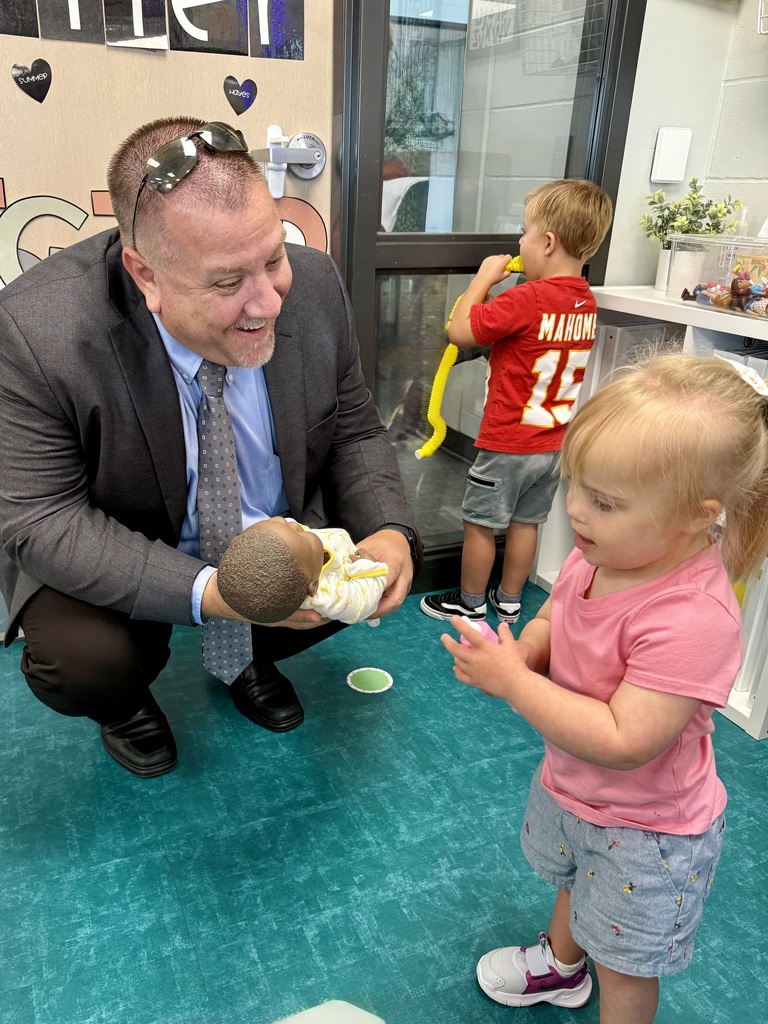 Superintendent Travis Lightle holding a baby doll for a student