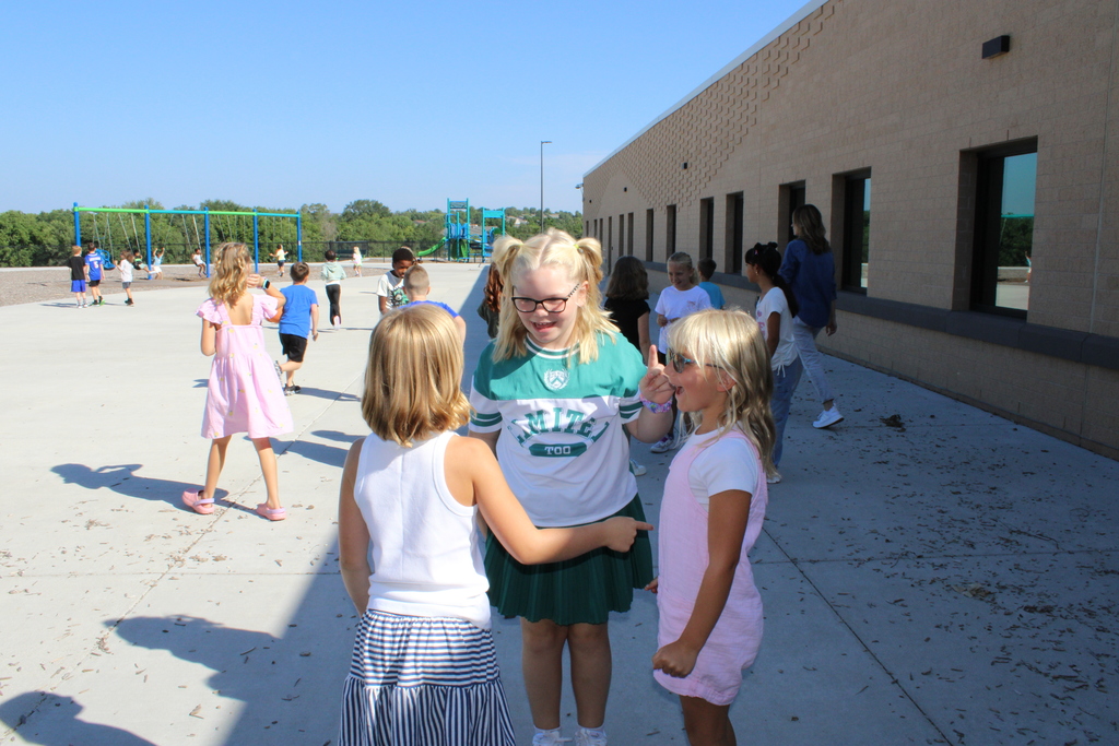 Girls chat and laugh together outside on the playground at recess.