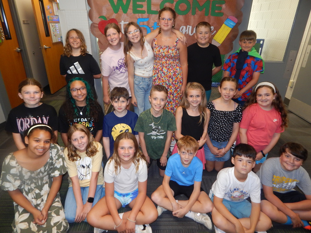 Group of 5th grade students, some standing and some sitting looking at the camera and smiling on the first day of school!