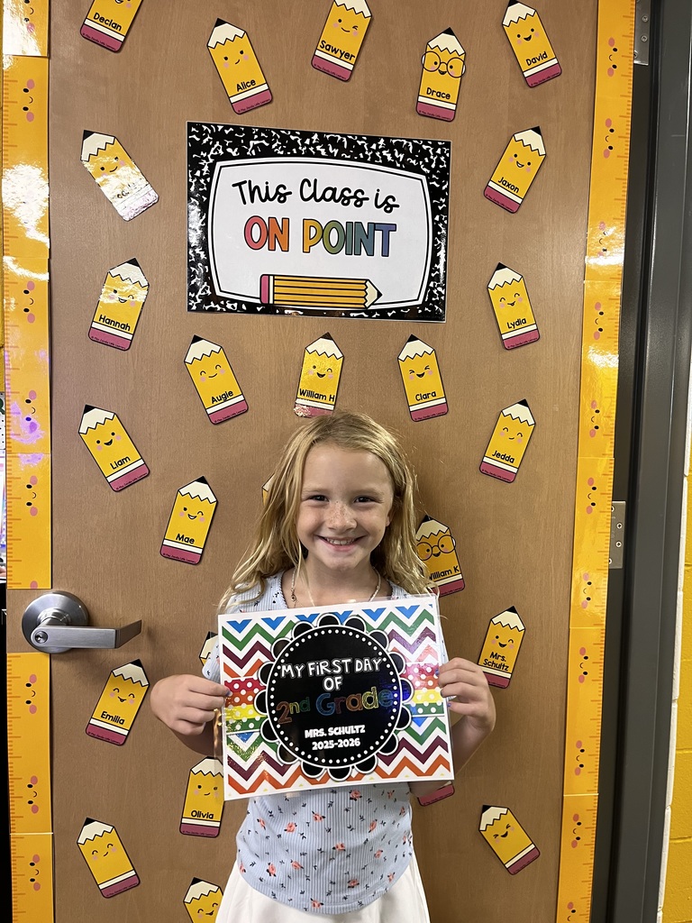 Student smiles for the camera holding a first day of first grade sign