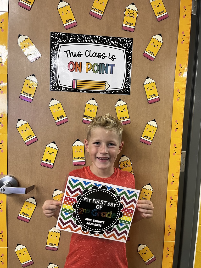 Student smiles for the camera holding a first day of first grade sign