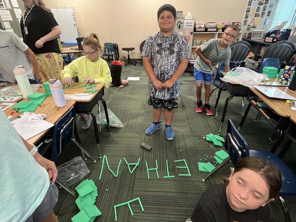 Boy standing on carpet with his name spelled out in place value blocks.