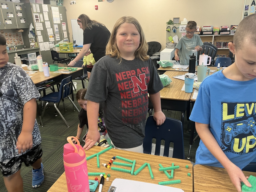 Girl standing in front of a desk with her name spelled out in place value blocks.