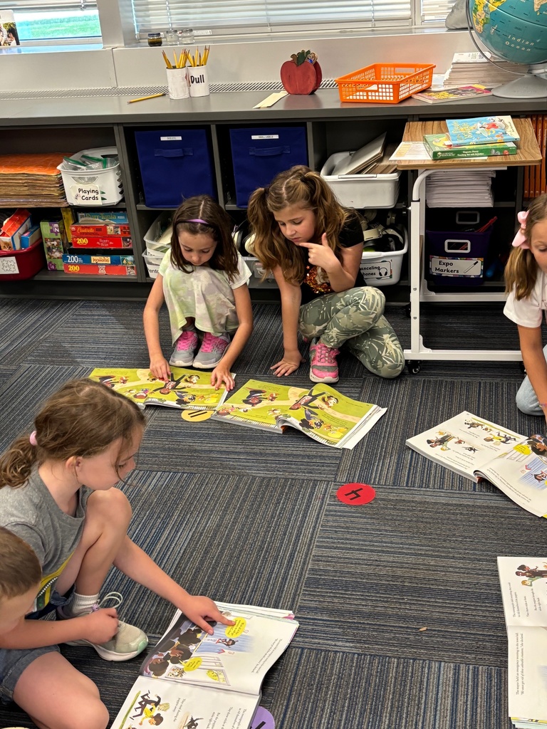 Three girls sitting on the ground looking at picture books.