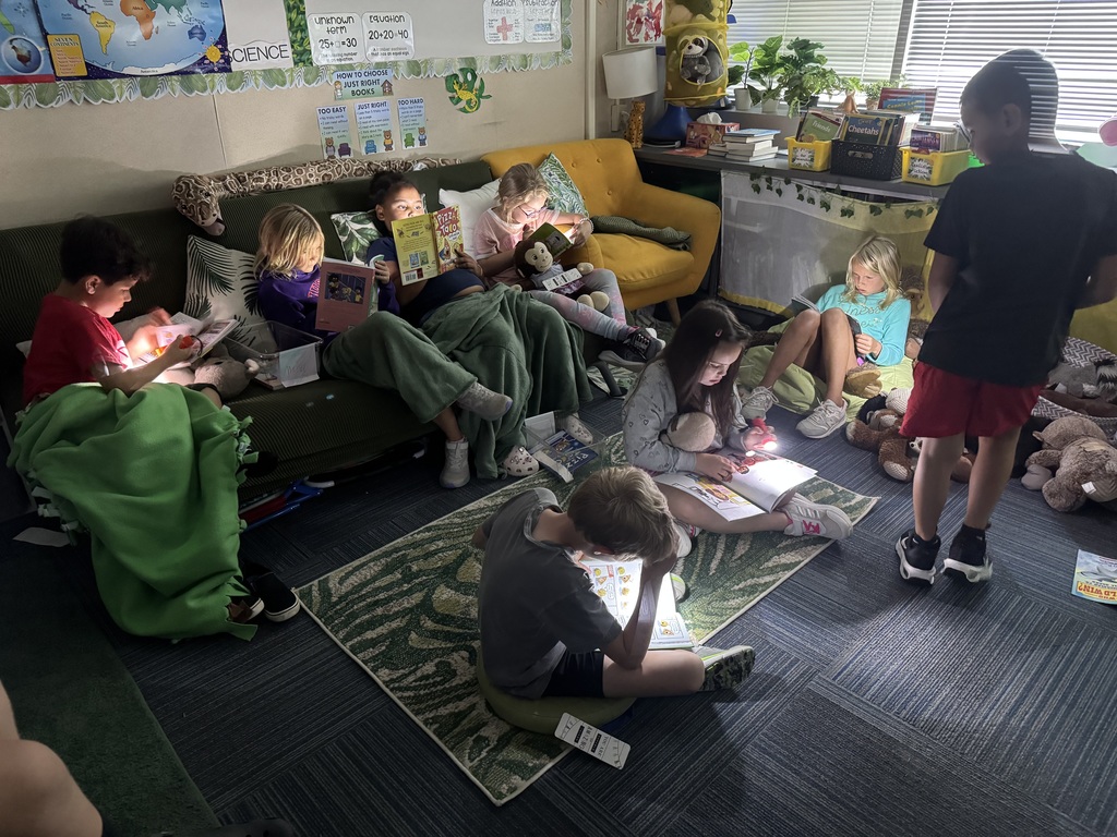 A group of students reading books in the dark with flashlights.