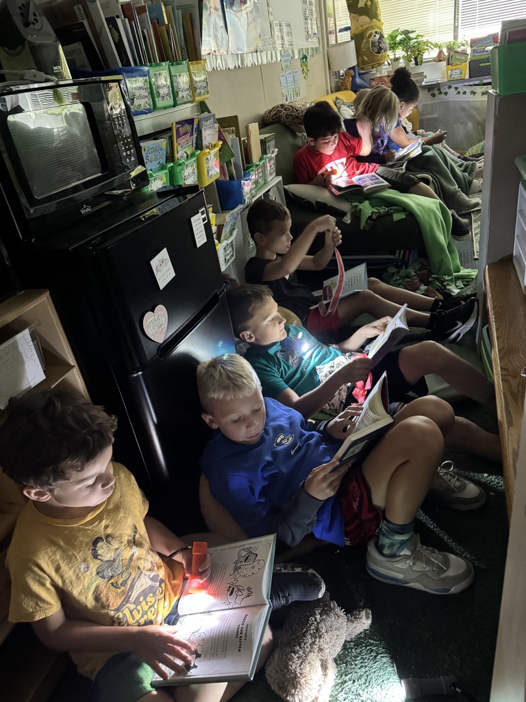 A group of students reading books in the dark with flashlights.