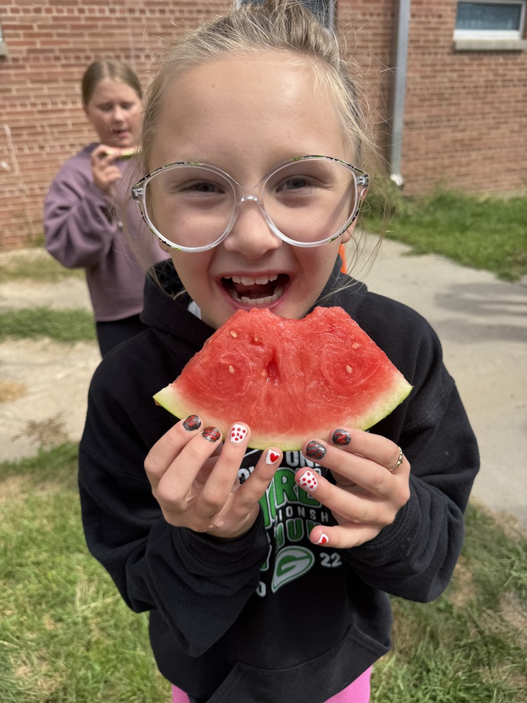 Girl smiles while holding a slice of watermelon.