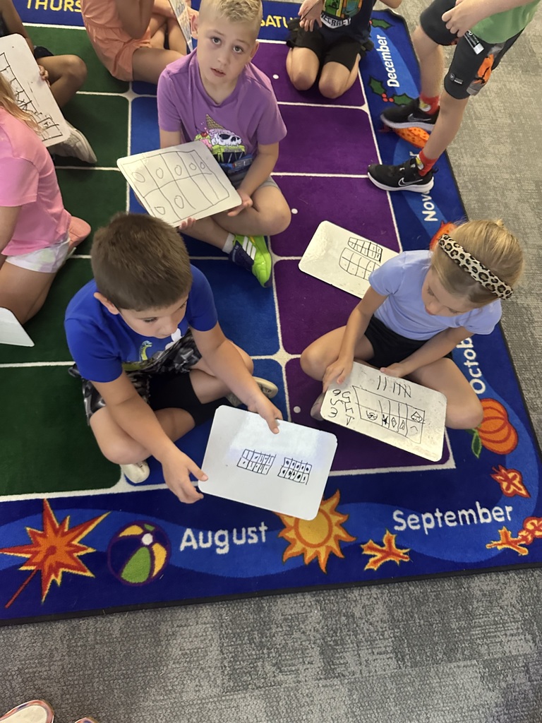 Students on the rug with whiteboards working on math