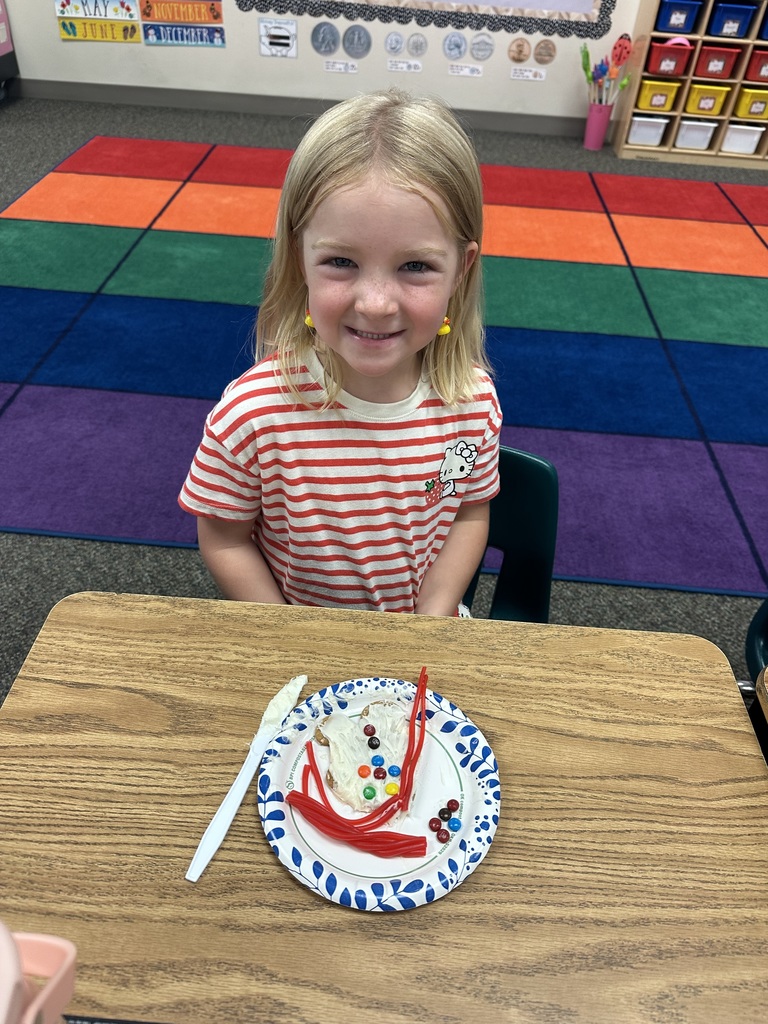 First grade student at desk smiling with gingerbread cookie