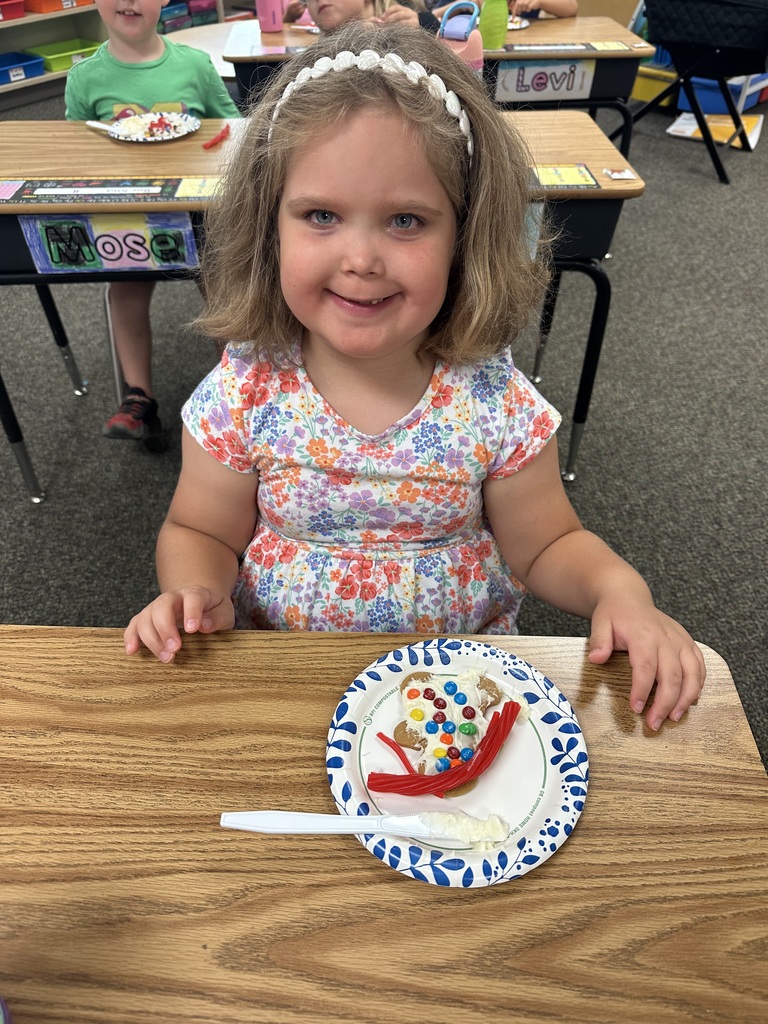 First grade student at desk smiling with gingerbread cookie