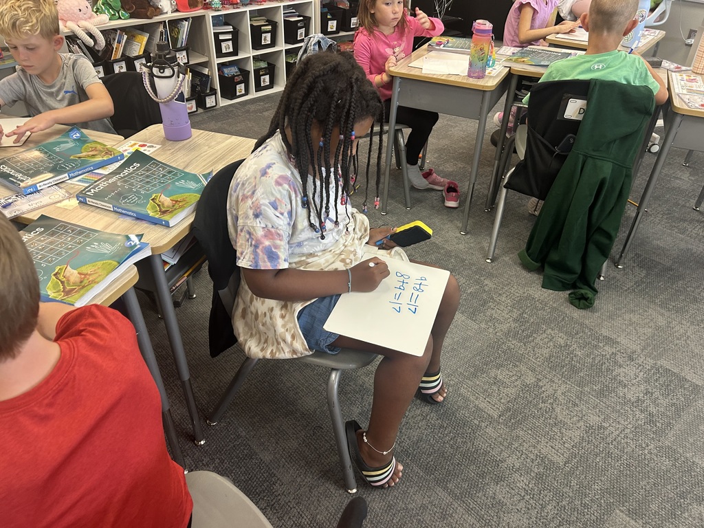 Mrs. Matousek and Mrs. Auman's 2nd grade students are working hard at math in a classroom at their seats using whiteboards. 