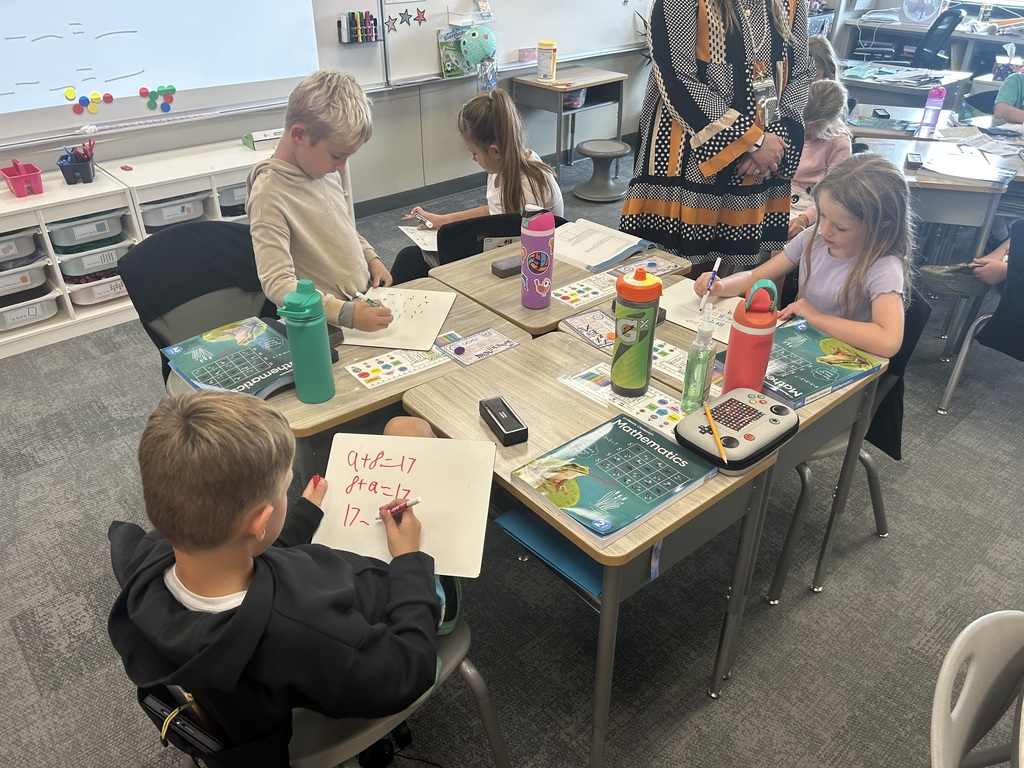 Mrs. Matousek and Mrs. Auman's 2nd grade students are working hard at math in a classroom at their seats using whiteboards. 