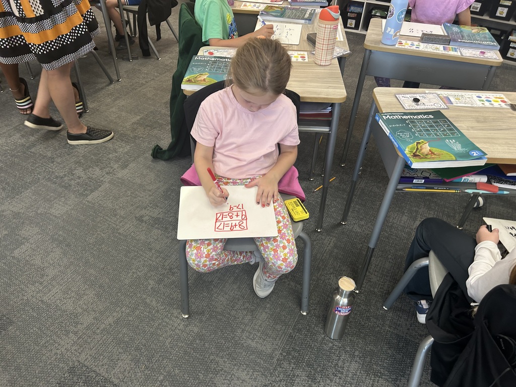 Mrs. Matousek and Mrs. Auman's 2nd grade students are working hard at math in a classroom at their seats using whiteboards. 