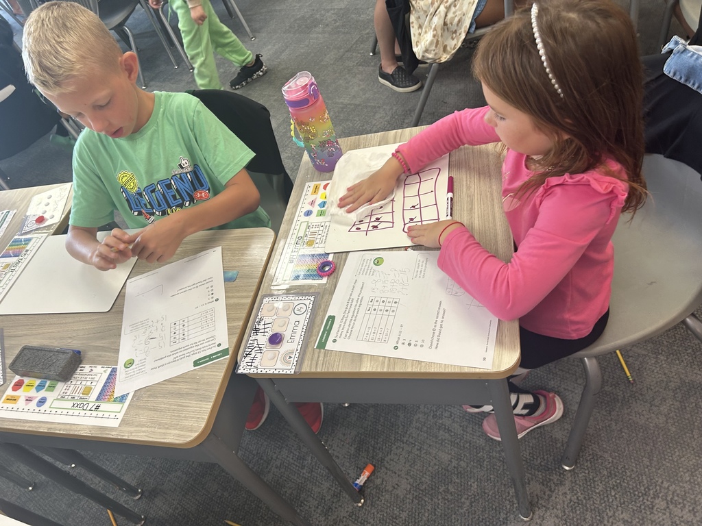 Mrs. Matousek and Mrs. Auman's 2nd grade students are working hard at math in a classroom at their seats using whiteboards. 