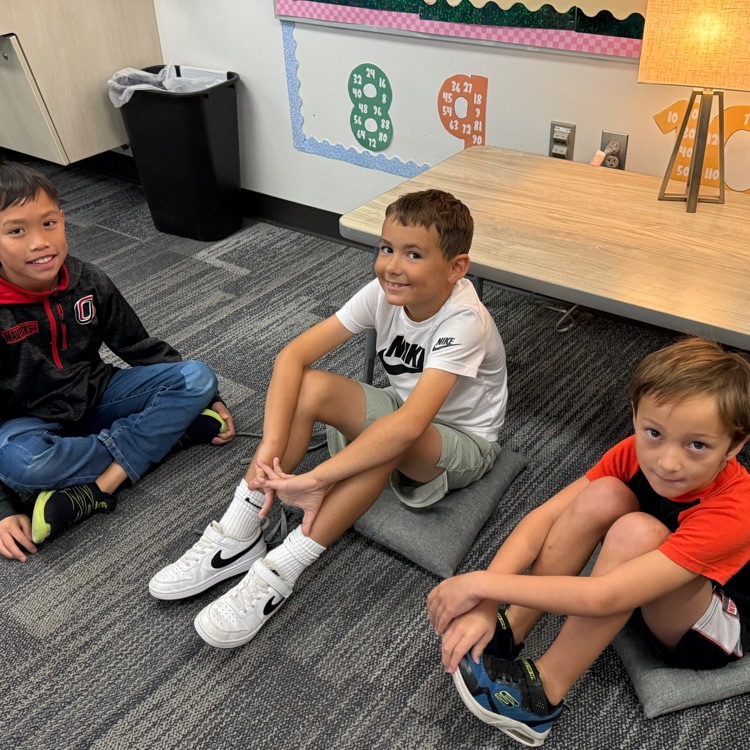 three male students sit together on the floor smiling