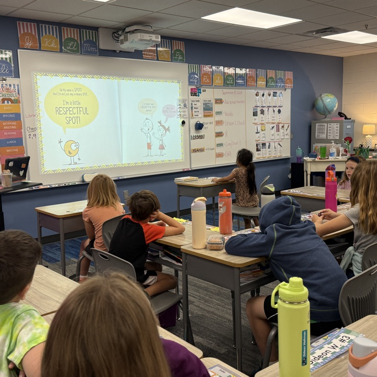 classroom of students looking at the screen showing a page out of the book “A Little Spot of Respect"