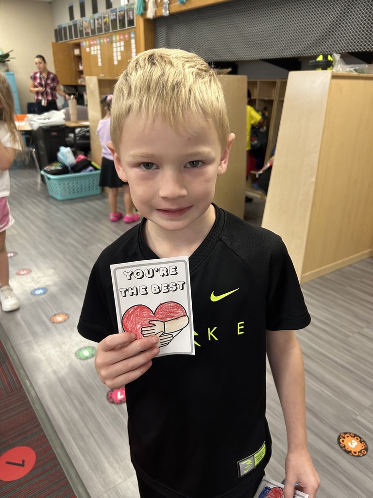 Boy holding up a piece of paper that says "You're the Best" with a heart.
