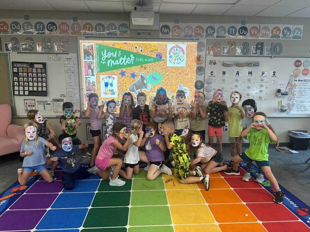 students posing with masks on a carpet