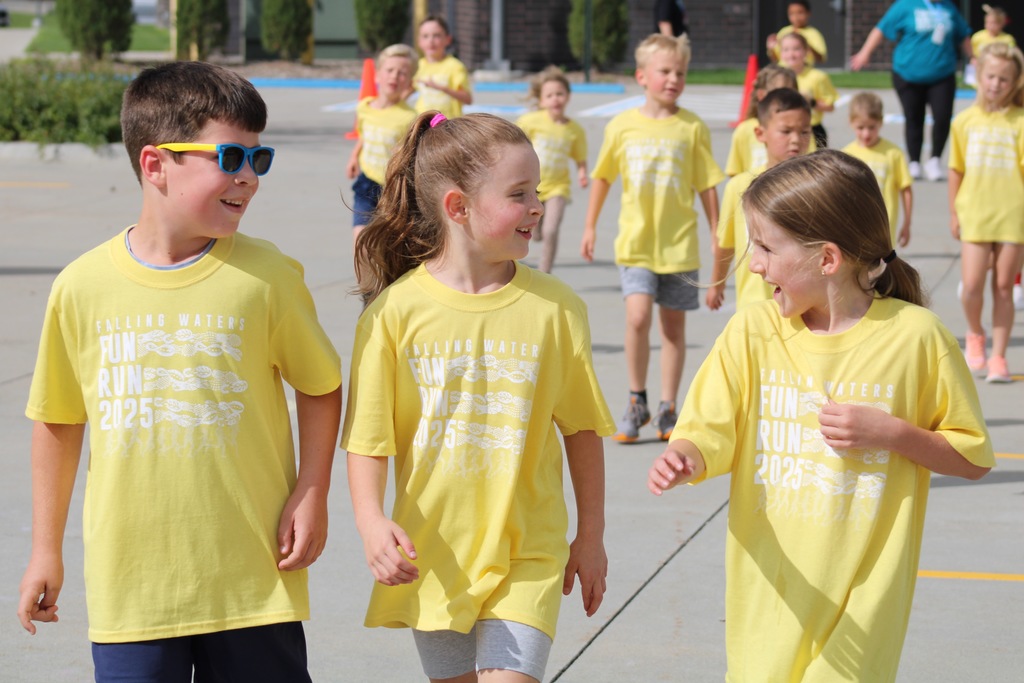 A group of 2nd graders in yellow shirts walking and laughing