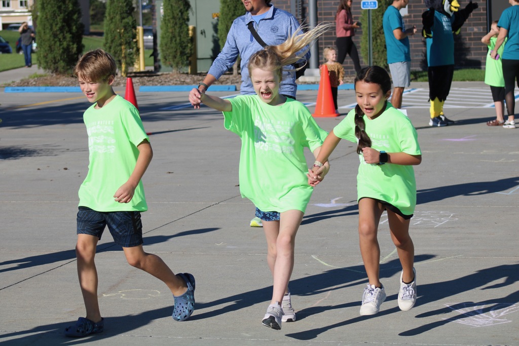 3 third graders in bright green shirts running