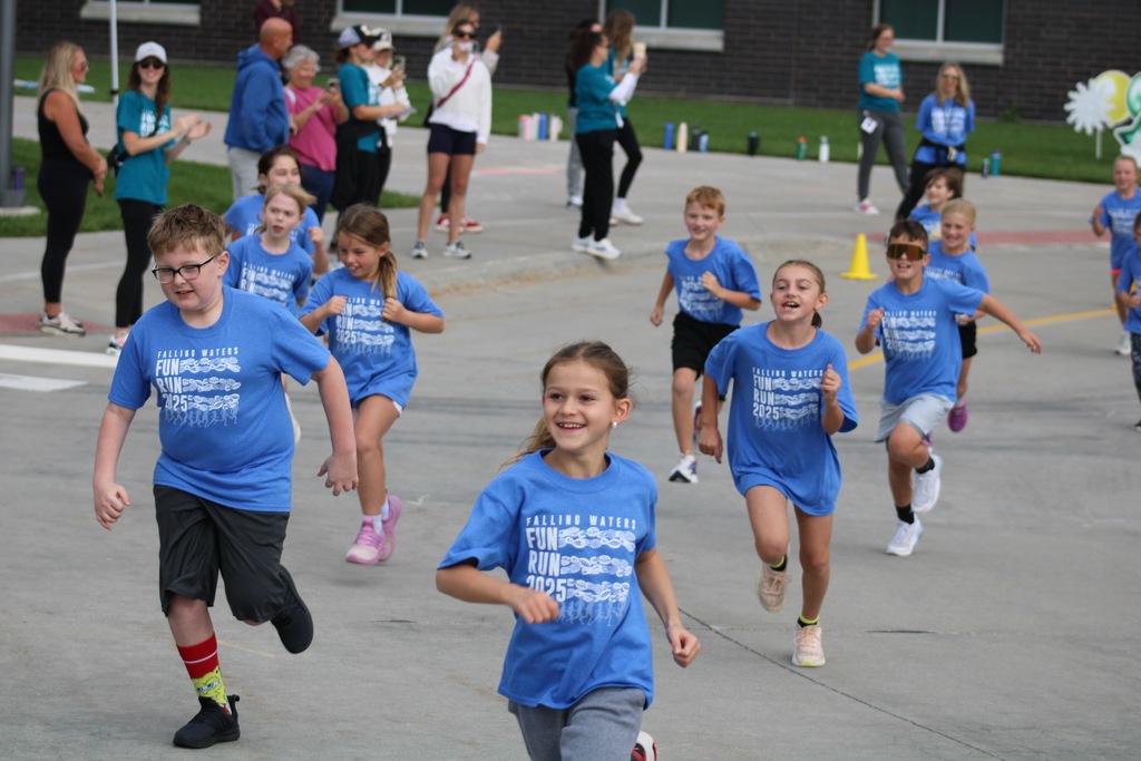 A group of 4th graders in blue shirts running