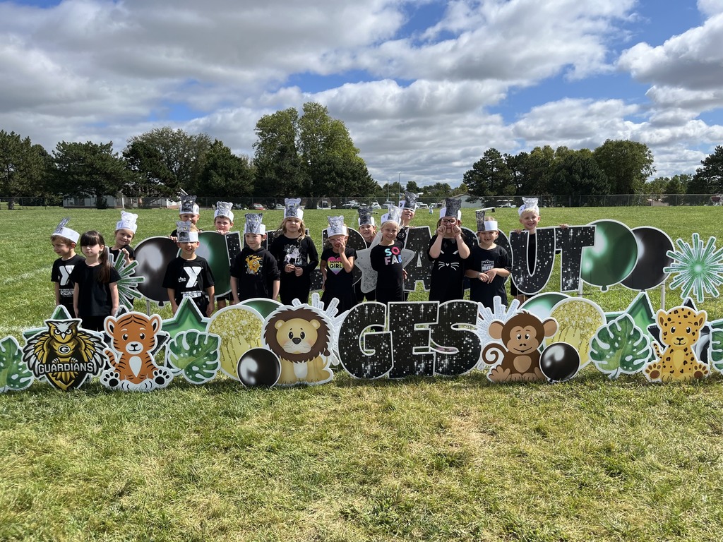 Group of students wearing black shirts in front of signs that show animals and GES.