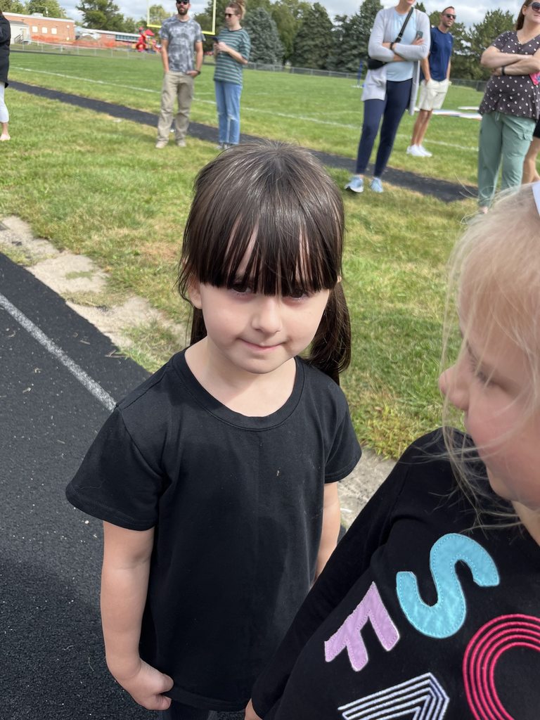 Student wearing black shirt looking at camera while standing on track.
