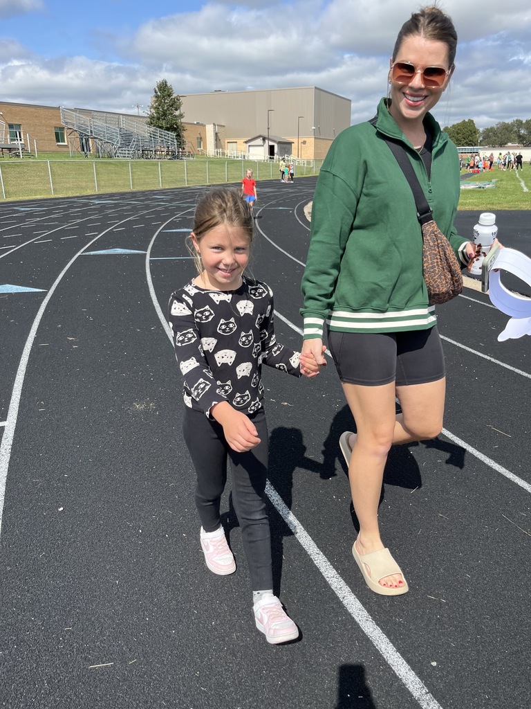 Girl and her mom holding hands on a running track.