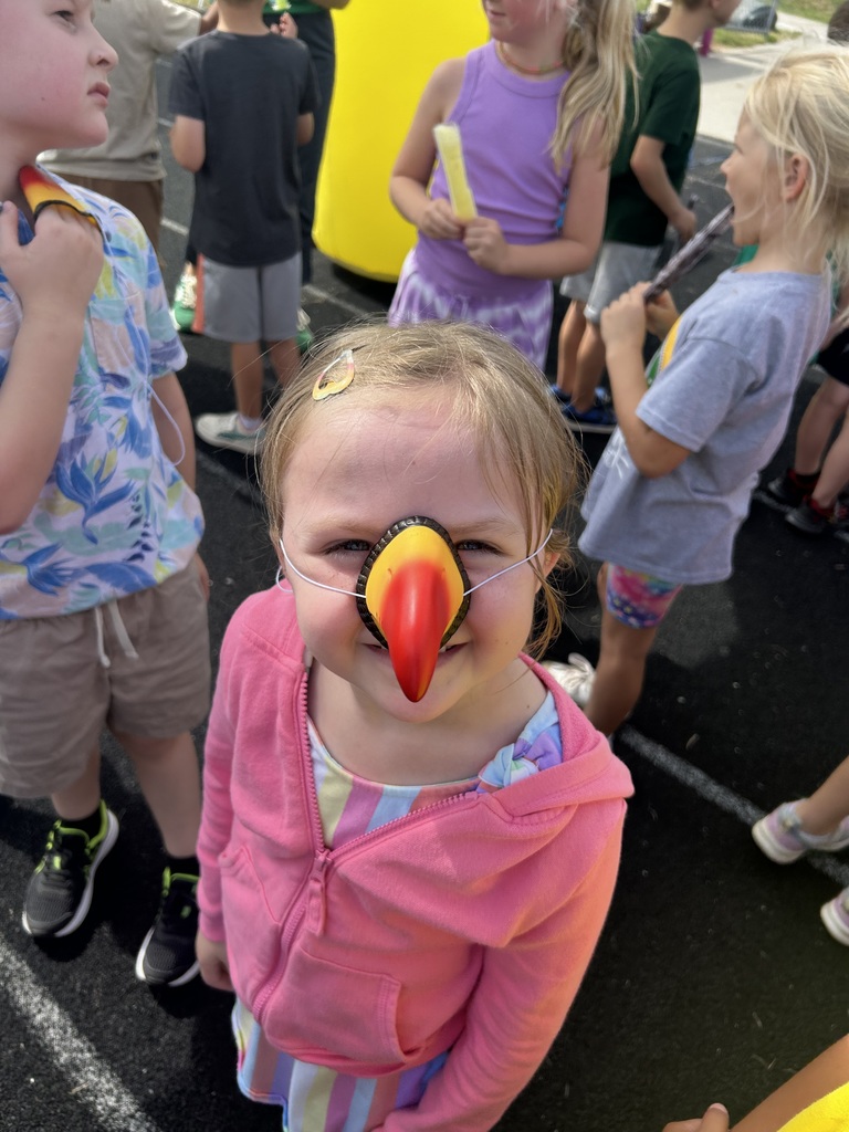 Girl smiling wearing a toucan beak wearing a pink jacket.