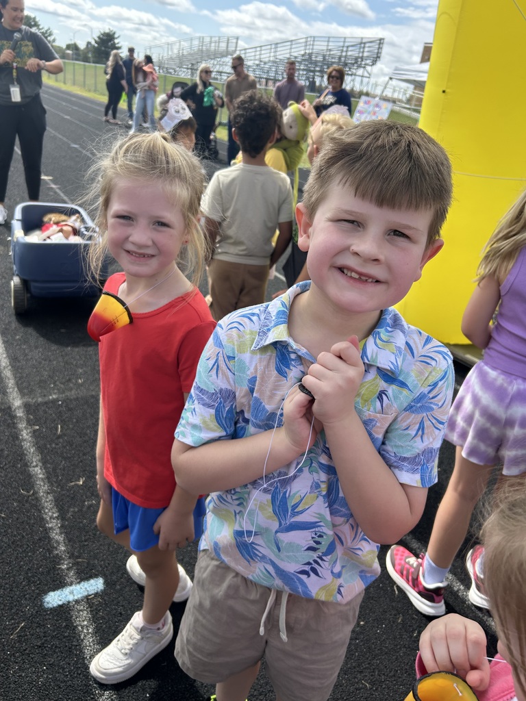 Two students standing wearing colorful shirts on a running track.