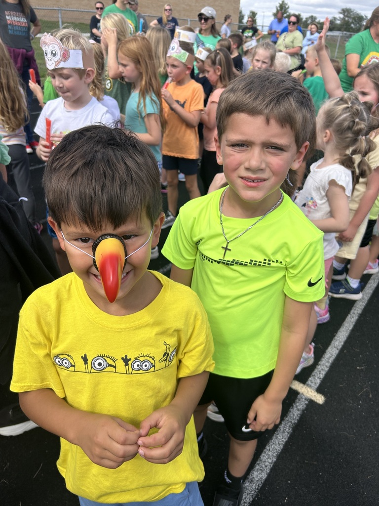 Two boys smiling, one wearing a toucan beak.  Both are wearing colorful shirts.
