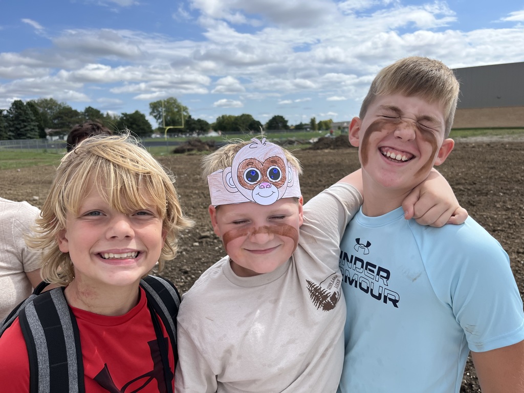 Three boys smiling with one wearing a monkey paper headband.  Two boys have face paint.